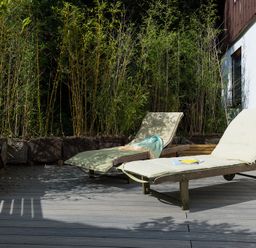 Two lounge chairs on a wooden deck with tall plants in the background at Sandy Hills 8 in Rock