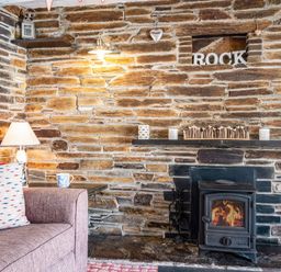 A stone wall with a burning wood stove mantel and a purple sofa with a pillow at St Michaels Rock