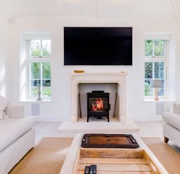A living room with a fireplace a large tv two sofas and windows at Greystones in Daymer Bay
