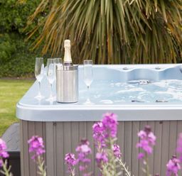 An outdoor hot tub with champagne bottle in ice bucket and four champagne flutes at Cherrytrees in Rock