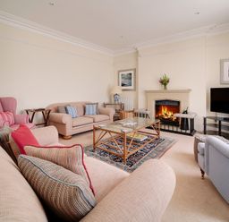 A living room with sofas armchairs a glass coffee table fireplace and a television at The Haven in Daymer Bay