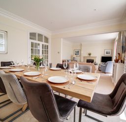 A dining table set with plates and glasses in a room with chairs and an adjoining living area at The Haven in Daymer Bay