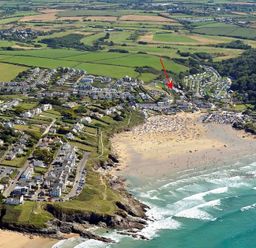 An aerial view of a coastal town with a beach fields houses and roads at Pendaveli in Polzeath