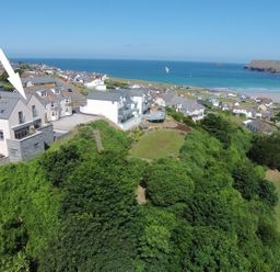 A coastal village with houses near a beach and green vegetation at Stepper Point in Polzeath