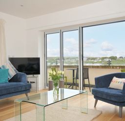 A living room with a sofa and coffee table overlooking a view at Stepper Point in Polzeath