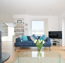 A living room with a fireplace and sofa at Stepper Point in Polzeath