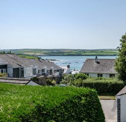 Houses with sloped roofs near a body of water with boats and green fields in the background at Drifters in Rock