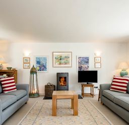 A living room with two grey sofas with striped pillows a fireplace and a television at Drifters in Rock