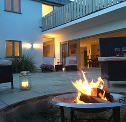An outdoor patio with a fire pit surrounded by wicker chairs and candles at Downalong in Daymer Bay