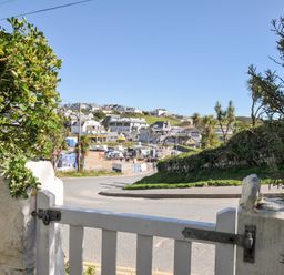 View of a street and beach area at Coppingers Cottage in Polzeath
