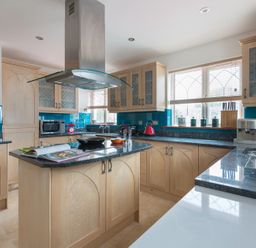A kitchen with wooden cabinets and a central island with a book and pan at Fairholme in Port Isaac