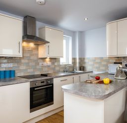 A kitchen with cabinets countertops stove oven and a window at The Hideaway in Port Isaac