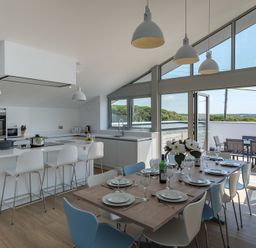 A kitchen with a dining table set with plates and glasses and an outdoor seating area at Point Break in Polzeath