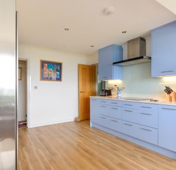A kitchen with blue cabinets wooden floor and kitchen utensils at Sea Mist in Polzeath