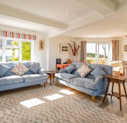 A living room with two blue sofas and patterned cushions at Trevan House Lundy in Polzeath