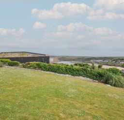A garden with grass and hedge overlooking the sea at Hillview in Polzeath