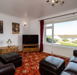 A living room with a television and views outside at Hillview in Polzeath