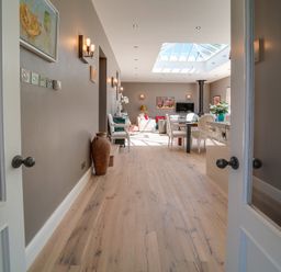 A view through open double doors into a living and dining area with wooden floors skylight and furniture at Trevanion in Rock