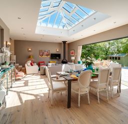 A dining area with a table and chairs next to a living area with sofas under a skylight at Trevanion in Rock