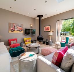 A living room with colorful chairs a round coffee table and a hanging fireplace at Trevanion in Rock