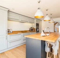A kitchen with wooden countertops and stools along an island at Seastar in Rock