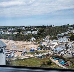 A coastal village with houses near a sandy beach and parked cars at Pinewood 14 in Polzeath