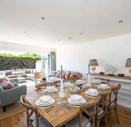 A dining area with a wooden table set for eight and a living area with sofas and armchairs at Artemis in Rock