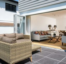An outdoor patio with wicker sofa and an indoor living room with sofas and a wooden dining table at Artemis in Rock