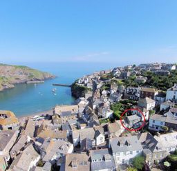 A coastal village with houses on a hillside and a bay with boats at Kipper Cottage in Port Isaac