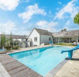 An outdoor swimming pool with a blue slide and lounge chairs near a white house at Landers Field in Rock