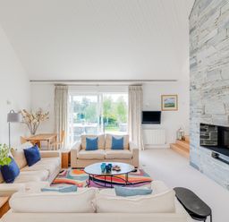 A living room with beige sofas blue pillows a stone fireplace and a sliding glass door at Landers Field in Rock