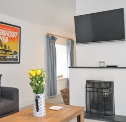 A living room with a TV and a fireplace at Orchard Cottage in Polzeath