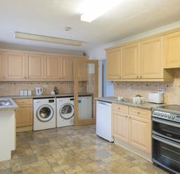 A kitchen with wooden cabinets a washing machine a dryer a dishwasher an oven and a toaster at Greenaway 4 Rockhaven Gardens in Rock