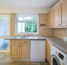 A kitchen with wooden cabinets a double sink a dishwasher a washing machine and a frosted glass door at Greenaway 4 Rockhaven Gardens Rock