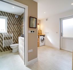 A utility room with a washing machine and a bathroom with a toilet and towel radiator at Seahaven Port Isaac