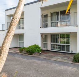 The exterior of a two story building with balconies shrubs and pavement at Westward 8 in Polzeath
