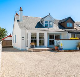 A white semi detached house with dormer windows and gravel driveway at Number 28 in Port Isaac