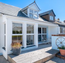 A porch with two large windows a small table with two chairs and potted plants at Number 28 in Port Isaac
