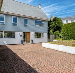 A front view of a two story house with blue siding and a paved driveway at Flaad House in Rock