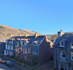 A street with parked cars and terraced houses with hills in the background at Squirrel Lodge in Keswick
