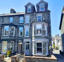 A stone terraced house with multiple windows and two dormer windows on the roof at Squirrel Lodge in Keswick
