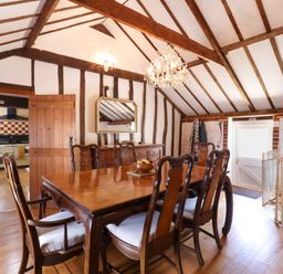 A dining room with a wooden table and chairs under exposed wooden beams at The Old Custom House in Wangford