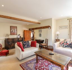 A living room with two sofas a wooden coffee table a wooden sideboard and framed pictures on the wall at The Old Custom House in Wangford