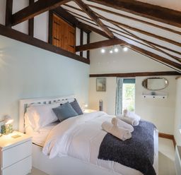A bedroom with a white bed and nightstands under exposed wooden beams at The Old Custom House in Wangford