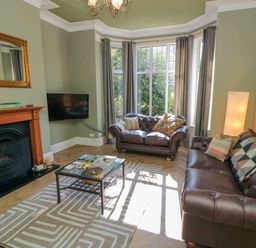 A living room with brown leather sofas a glass coffee table a fireplace and a wall mounted tv at South Bay House in Scarborough