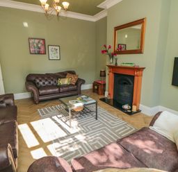 A living room with brown leather sofas a glass coffee table and a fireplace at South Bay House in Scarborough