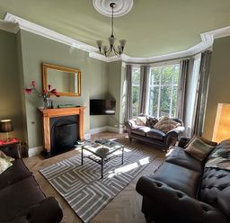 A living room with two sofas a fireplace a coffee table and large windows at South Bay House in Scarborough