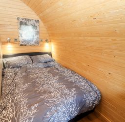 A bedroom with a double bed and wooden walls at Gander Pod Near Clifton Upon Teme