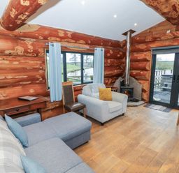 A living room with a sofa, fireplace, and table at Cedar Cabin at Salford Court Farm Fishing Cabins near Clifton Upon Teme