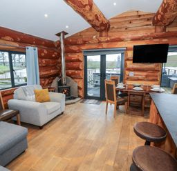 A living room with a sofa and dining area at Cedar Cabin at Salford Court Farm Fishing Cabins near Clifton Upon Teme
